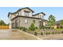 A modern home features stone accents, a driveway, and landscaping, blending contemporary and natural aesthetics at 8623 S Wadsworth Ct, Littleton, CO 80128