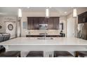 A spacious kitchen featuring a large island with quartz countertop and dark wood cabinets at 3153 Eagle Claw Pl, Castle Rock, CO 80108