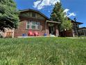 Lush green lawn with a charming red brick home featuring a covered porch, ideal for outdoor enjoyment at 726 S Corona St, Denver, CO 80209