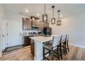 Well-lit kitchen featuring a quartz island with seating, modern lighting, and stainless steel appliances at 16433 Askins Loop, Parker, CO 80134