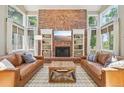 Cozy living room with a brick fireplace, built-in bookshelves, and large windows at 5528 S Jasper Way, Centennial, CO 80015
