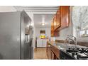 A kitchen with stainless steel appliances, wooden cabinets, and access to laundry at 5942 Poplar St, Commerce City, CO 80022