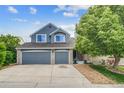 Charming two-story home features a two car garage, a well-manicured front yard, and blue siding at 8927 Green Meadows Ln, Highlands Ranch, CO 80126