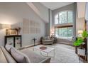 Bright living room with soaring ceilings, modern decor, and a large arched window overlooking the yard at 8927 Green Meadows Ln, Highlands Ranch, CO 80126