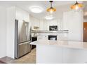 Bright kitchen with white cabinets, stainless steel refrigerator, and peninsula island at 9150 E Center Ave # 9C, Denver, CO 80247