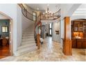 Grand foyer features a curved staircase, stone floors, and elegant chandelier at 9009 Rambling Oak Pl, Parker, CO 80134