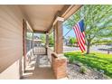 Inviting front porch with an American flag and a glimpse of the well-kept neighborhood at 10289 Dresden St, Firestone, CO 80504