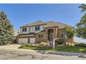 Charming two-story brick home with a well-manicured front yard and a two-car garage during the daytime at 16261 W Ellsworth Ave, Golden, CO 80401