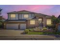 Charming two-story brick home with a well-manicured front yard and a two-car garage at dusk at 16261 W Ellsworth Ave, Golden, CO 80401