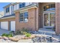Close-up of the front entrance with brick facade, security door, and landscaped garden at 16261 W Ellsworth Ave, Golden, CO 80401