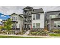 Three-story townhome featuring a red front door, stone accents, and dual upper level balconies at 16546 Umatilla Place, Broomfield, CO 80023