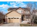 Charming two-story home featuring a tan and brown exterior, a front porch, an attached garage, and solar panels on the roof at 5563 S Elk Ct, Aurora, CO 80016