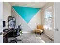 Bright office featuring a unique teal and gray accent wall, a desk, and a cozy yellow chair by a sunlit window at 5563 S Elk Ct, Aurora, CO 80016