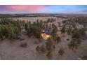 Aerial shot of an estate nestled among mature trees with a picturesque landscape and a vibrant sunset at 121 County Road 146, Elizabeth, CO 80107