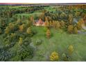 An aerial view showing a large home surrounded by lush green fields, and mature trees at 121 County Road 146, Elizabeth, CO 80107