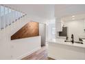 Bright entryway features wood floors, modern kitchen with white countertops, and staircase with a wooden accent wall at 8197 S Fillmore Way, Centennial, CO 80122