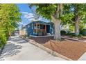 Blue home exterior with landscaped front yard, long driveway, modern porch railing, and mature trees at 2577 Depew St, Edgewater, CO 80214