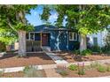 Quaint blue home features a well-manicured front yard with lush trees and a welcoming entrance at 2577 Depew St, Edgewater, CO 80214