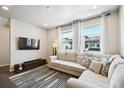 Sunlit living room with a comfortable sofa, contemporary rug, and large windows with stylish curtains at 19221 E 65Th Ave, Denver, CO 80249