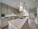 Bright kitchen features grey cabinets, a granite island with sink, and modern pendant lighting at 12979 E 103Rd Pl, Commerce City, CO 80022