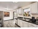 Modern kitchen with white cabinets, black countertops, stainless steel appliances, and a view out the window at 8361 Mason Cir, Westminster, CO 80031