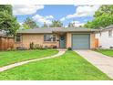 Charming brick home with a well-manicured lawn, a curved walkway, and a freshly painted garage door at 1060 S Harrison St, Denver, CO 80209