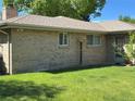 Green backyard with healthy lawn, traditional brick exterior, and white-trimmed windows at 1602 S Lamar St, Lakewood, CO 80232