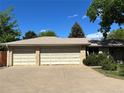 Spacious three-car garage with an expansive concrete driveway and brick exterior at 1602 S Lamar St, Lakewood, CO 80232
