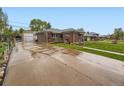 View of the brick house with a long driveway, detached garage, and fenced yard at 5721 Everett St, Arvada, CO 80002