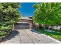 Beautiful brick home with a well-manicured lawn, mature trees, and a spacious two-car garage at 12344 Turquoise Terrace St, Castle Pines, CO 80108