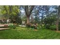 Lush backyard featuring a deck and seating area surrounded by mature trees and colorful flowers at 308 Baron Ave, Lafayette, CO 80026