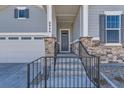 Inviting front porch with gray siding, stone accents, and a black metal railing at 8946 S Rome Ct, Aurora, CO 80016