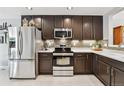 Modern kitchen with stainless steel appliances, dark cabinets, and light countertops at 5656 S Sicily Ct, Aurora, CO 80015