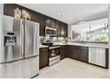 Well-lit kitchen with stainless steel appliances, dark wood cabinets, and a mosaic tile backsplash at 5656 S Sicily Ct, Aurora, CO 80015