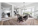 Open concept dining area with stylish chandelier, wood floors, modern furniture, and view of the updated kitchen at 20765 E 39Th Ave, Denver, CO 80249