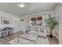 Bright living room with stylish flooring, a comfy sofa, and lots of natural light from the large window at 3090 W Longfellow Pl, Denver, CO 80221