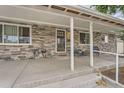 Inviting covered front porch with stone veneer and neutral trim at 2701 S Knox Ct, Denver, CO 80236