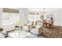 Bright living room with hardwood floors, large windows, comfortable seating, and a view of the adjacent dining area at 6385 S Nelson Way, Littleton, CO 80127