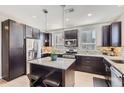 Modern kitchen features dark cabinets, stainless steel appliances, pendant lights and a large center island with bar seating at 3795 Depew St # D, Wheat Ridge, CO 80212