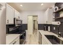 Galley kitchen featuring white cabinets, stainless steel appliances, and herringbone backsplash at 4068 S Atchison Way # 101, Aurora, CO 80014
