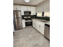 Bright kitchen boasts stainless steel appliances, white cabinetry and dark tiled backsplash at 1273 Newark St, Aurora, CO 80010