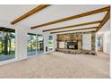 Inviting living room featuring wood beam ceilings, a cozy stone fireplace, large windows, and plush carpeting at 9212 Tanglewood Rd, Franktown, CO 80116