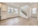 Open concept living space with wood-look floors, staircase, and abundant natural light from large windows at 7308 Waterleaf Trl, Littleton, CO 80125