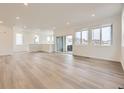 Spacious living room with wood-look floors, recessed lighting, and ample natural light at 7308 Waterleaf Trl, Littleton, CO 80125