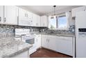 Bright kitchen with white cabinets, tile backsplash, granite countertops, and stainless steel appliances at 8666 Decatur St # 254, Westminster, CO 80031