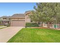 Inviting home with a manicured lawn, mature trees, and a stone-accented facade at 23882 E Alabama Dr, Aurora, CO 80018