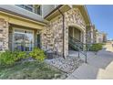 Apartment building entrance with stone accents, green door, landscaping, and walkway at 18657 Stroh Rd # 4103, Parker, CO 80134