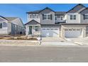 Two-story townhome with gray and white siding, two-car garage, and a paved driveway at 6575 N Nepal St, Aurora, CO 80019