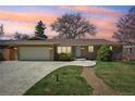 Attractive brick home with manicured lawn, an attached garage, and a patterned concrete driveway during sunset at 2243 S Olive St, Denver, CO 80224