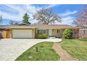 Inviting brick home with well-kept landscaping, an attached garage, and decorative concrete driveway on a sunny day at 2243 S Olive St, Denver, CO 80224